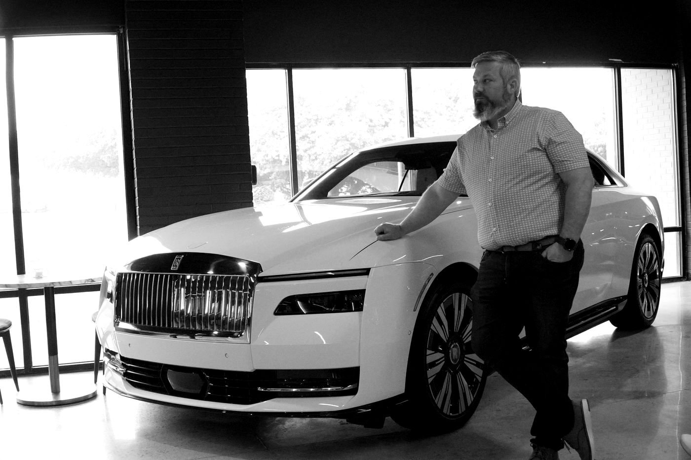 Justin standing beside a Rolls-Royce Spectre in a showroom during prototype review